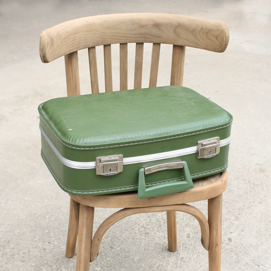 Valise vintage verte sur chaise en bois